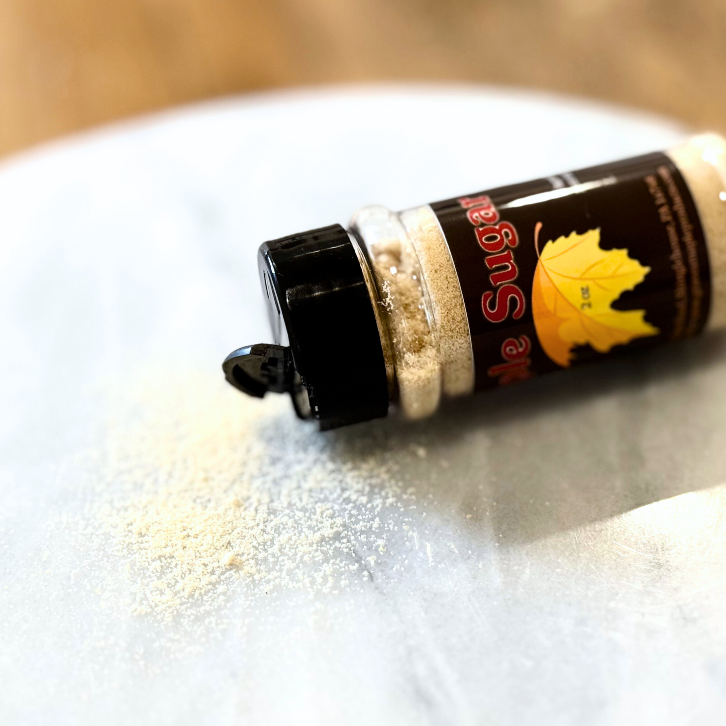 Maple sugar spilled from 2 oz shaker – Graves Maple Products on marble surface
