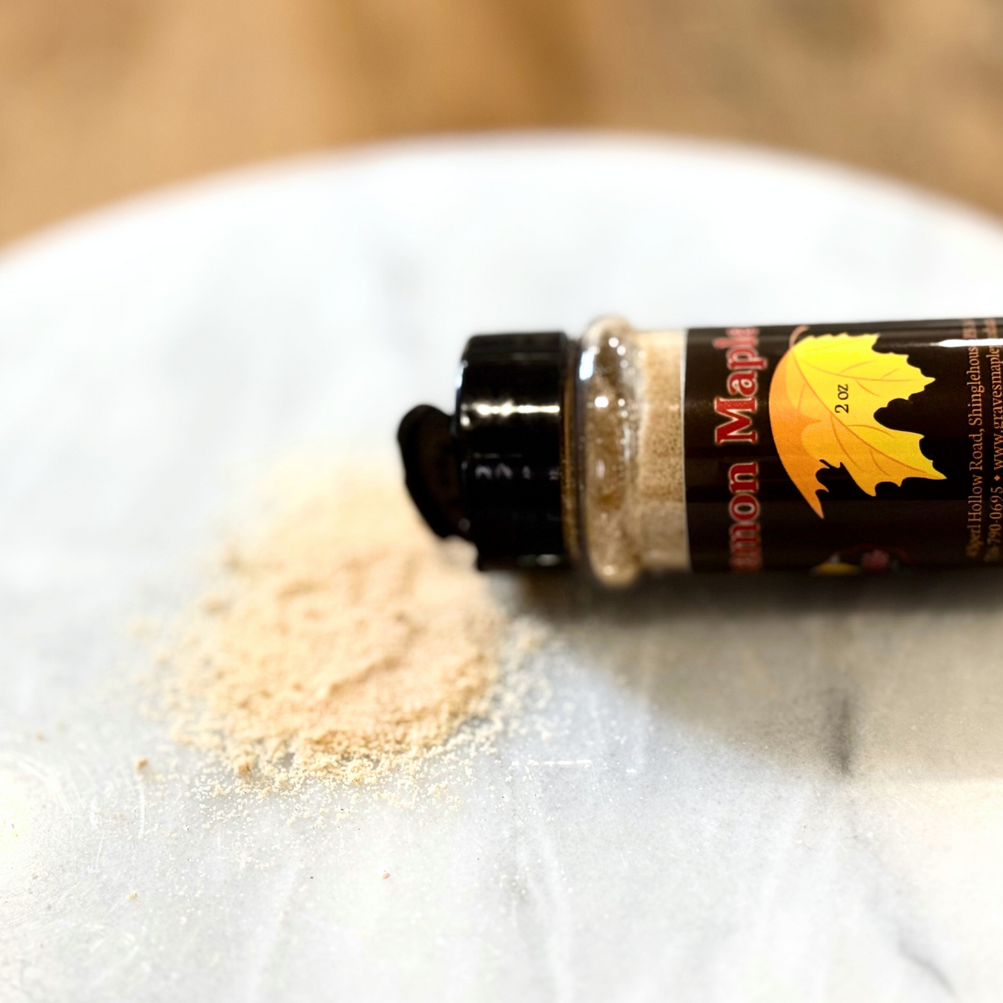 Cinnamon maple sugar spilled from 2 oz shaker – Graves Maple Products on marble surface