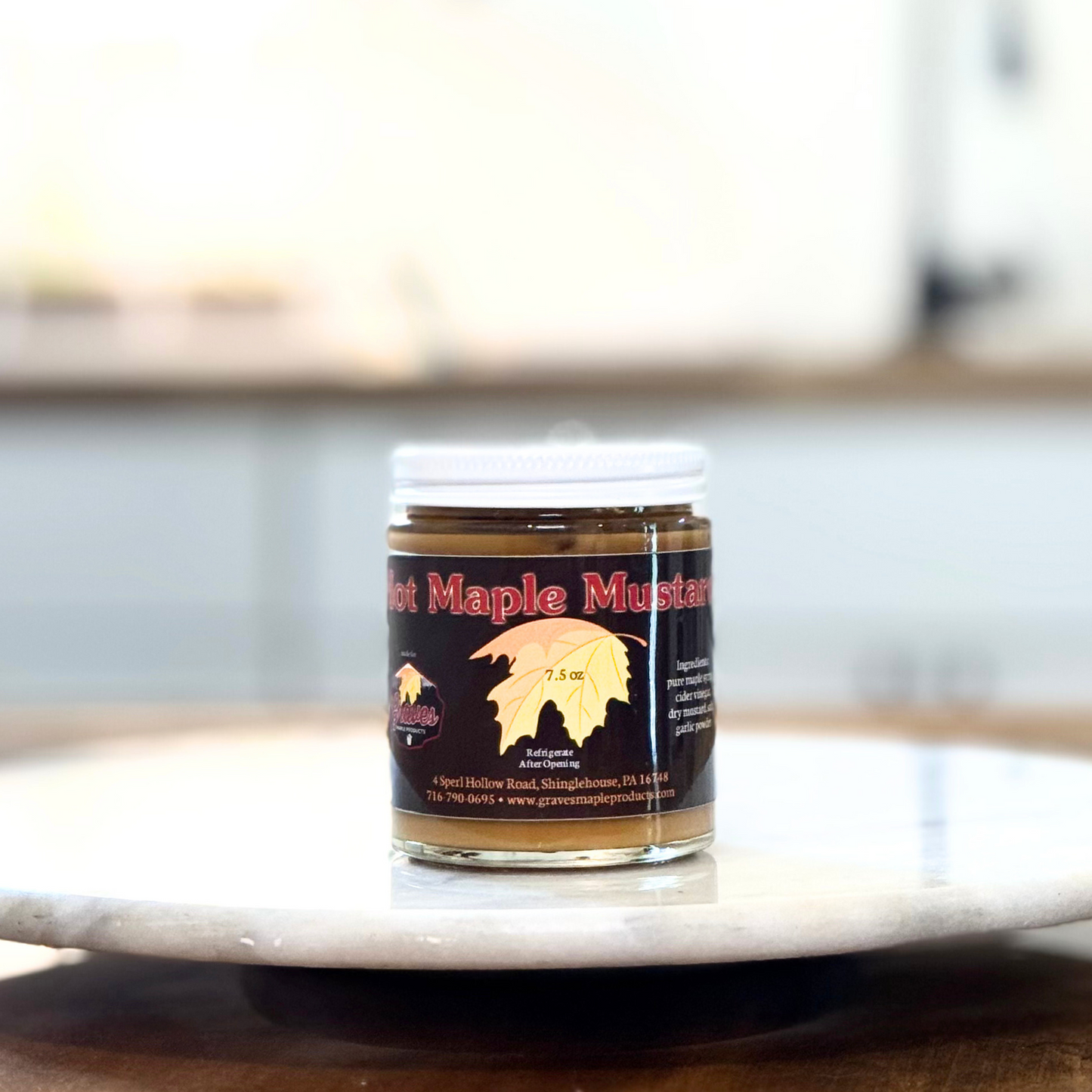 Jar of hot maple mustard on a marble surface with a blurred background