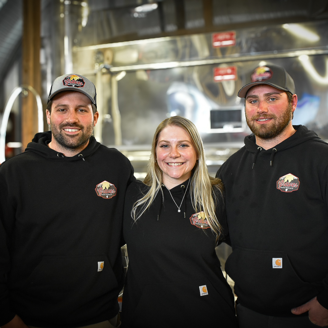 raves Maple Products team members in front of stainless steel maple syrup machinery – inside the sugarhouse during syrup production season.